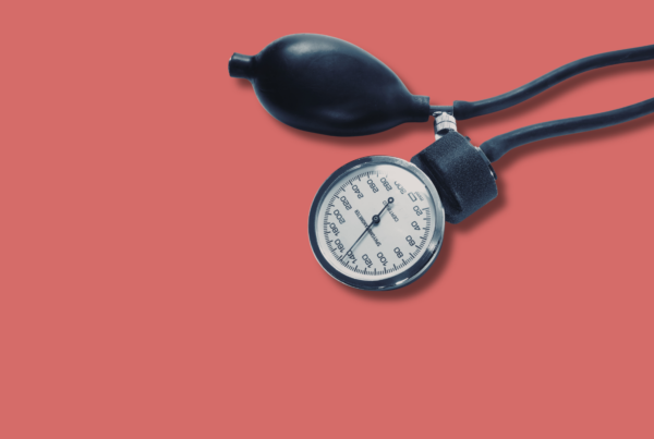 sfigmomanometro per misurare la pressione su sfondo rosa uniforme